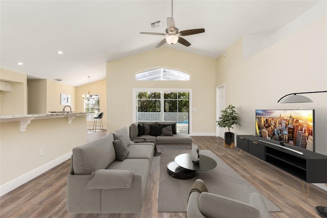 living room featuring ceiling fan with notable chandelier, high vaulted ceiling, and dark wood-type flooring