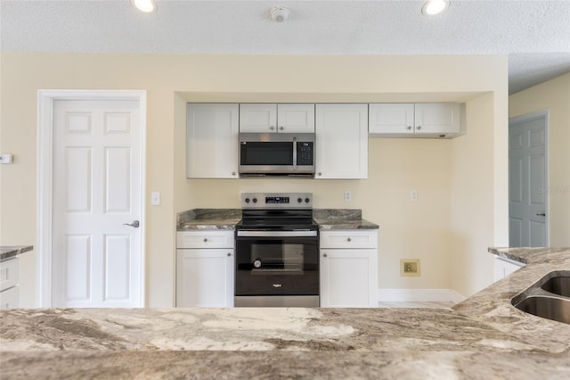 kitchen featuring appliances with stainless steel finishes, a textured ceiling, light stone countertops, and white cabinets