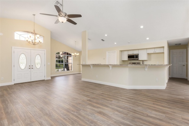 interior space featuring hardwood / wood-style flooring, high vaulted ceiling, and ceiling fan with notable chandelier