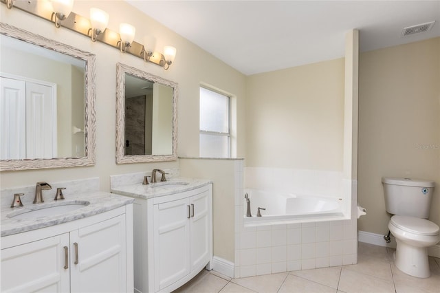 bathroom with tile patterned flooring, vanity, tiled bath, and toilet