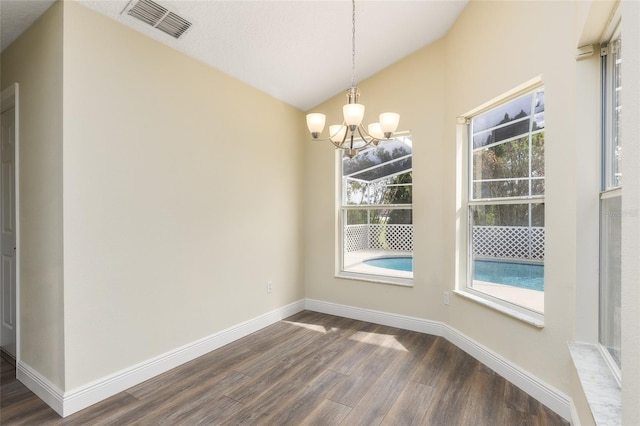 unfurnished dining area featuring dark wood-type flooring, a chandelier, and lofted ceiling