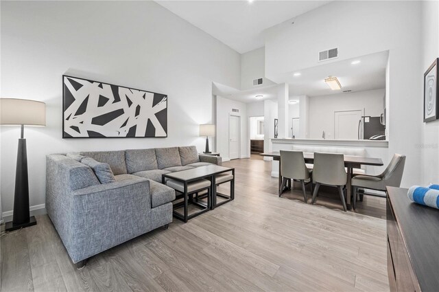 living room with light hardwood / wood-style floors and a towering ceiling