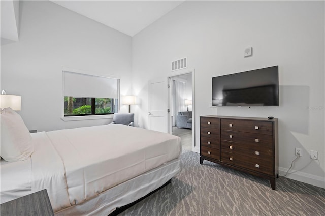 carpeted bedroom with visible vents, high vaulted ceiling, and baseboards