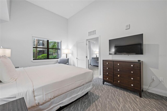 carpeted bedroom with high vaulted ceiling