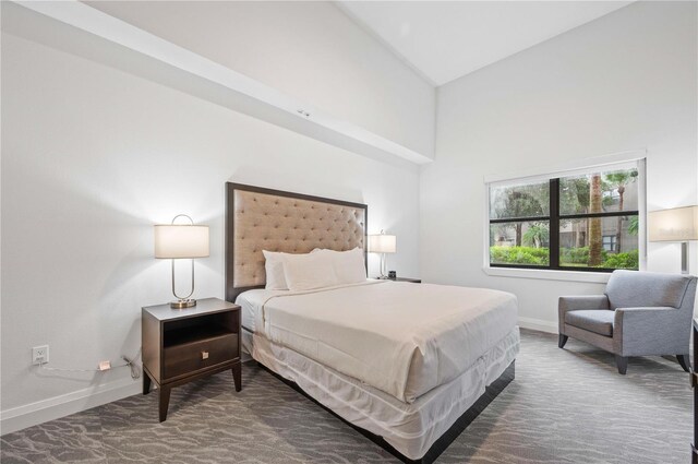 bedroom with high vaulted ceiling and dark colored carpet