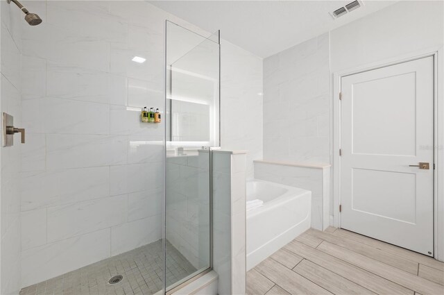 bathroom with independent shower and bath and wood-type flooring