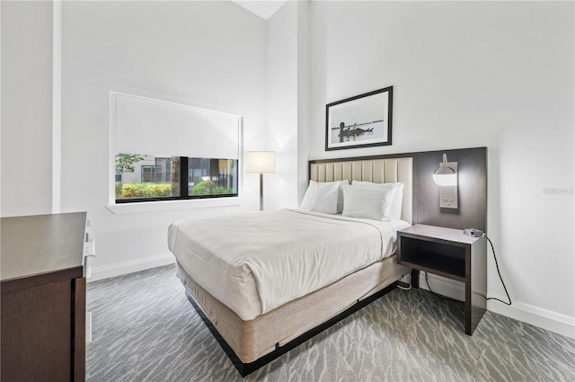 bedroom with a high ceiling and baseboards
