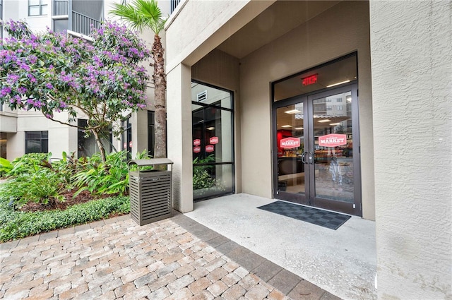 view of exterior entry featuring french doors and stucco siding