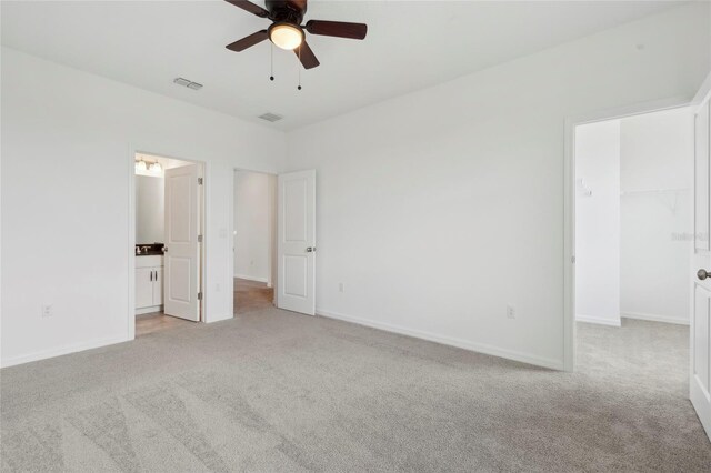 unfurnished bedroom with light carpet, a closet, ceiling fan, and a spacious closet