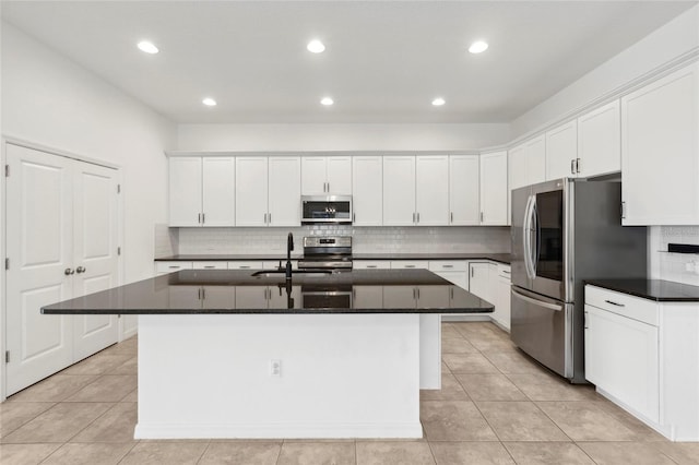 kitchen featuring an island with sink, appliances with stainless steel finishes, backsplash, and white cabinetry