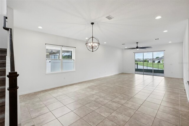 empty room with ceiling fan with notable chandelier and light tile patterned floors