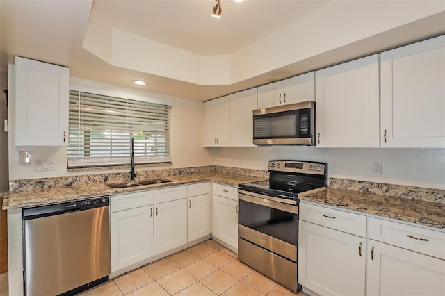 kitchen with sink, stainless steel appliances, white cabinets, and light tile patterned floors