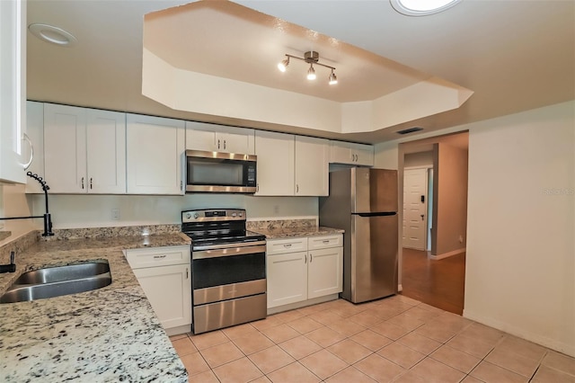 kitchen with white cabinets, light tile patterned floors, light stone countertops, and stainless steel appliances