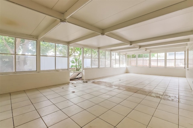 unfurnished sunroom featuring beam ceiling and a healthy amount of sunlight