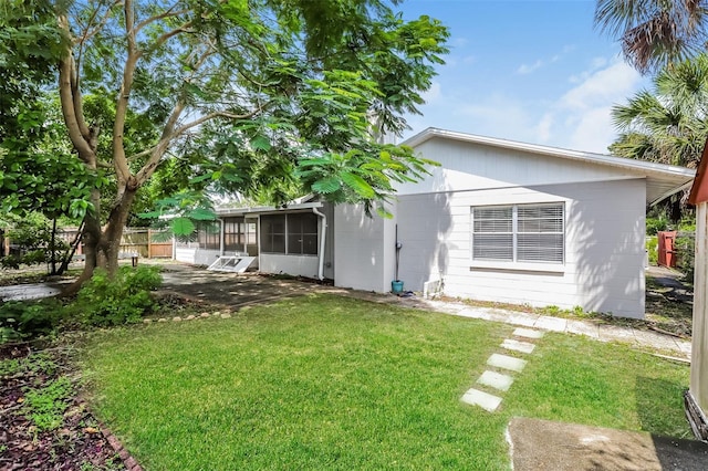 back of house with a sunroom, a yard, and concrete block siding