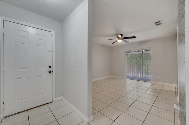 tiled entryway with ceiling fan and a textured ceiling