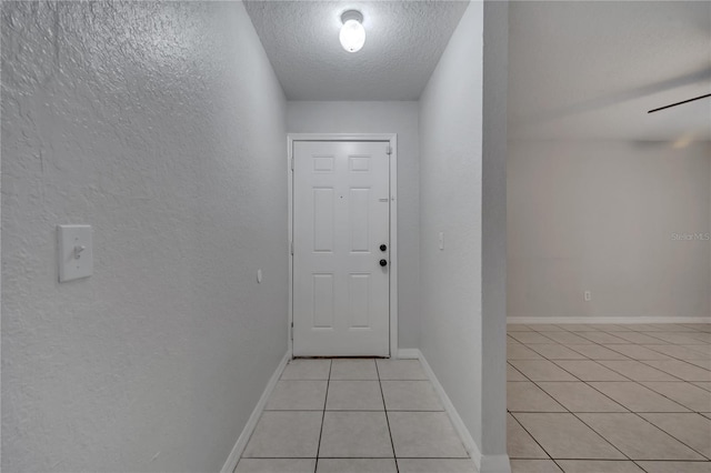 doorway featuring a textured ceiling and light tile patterned floors