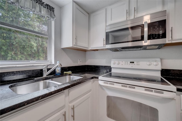 kitchen with sink, white cabinets, electric range, and dark stone counters