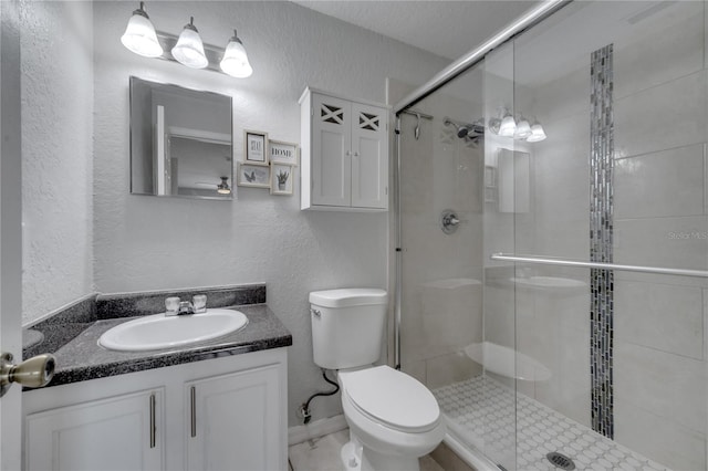 bathroom with a textured ceiling, a shower with door, vanity, and toilet