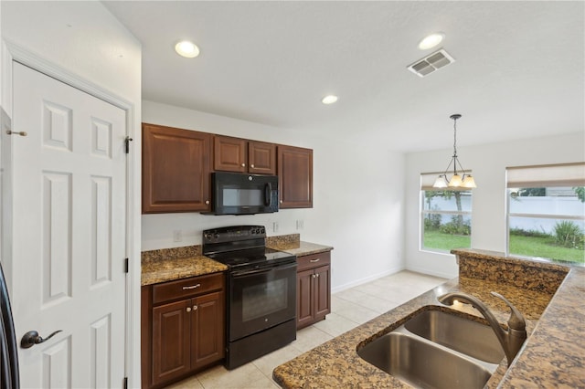 kitchen with pendant lighting, black appliances, sink, dark stone countertops, and light tile patterned floors