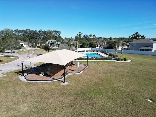 view of home's community with a pool and a yard