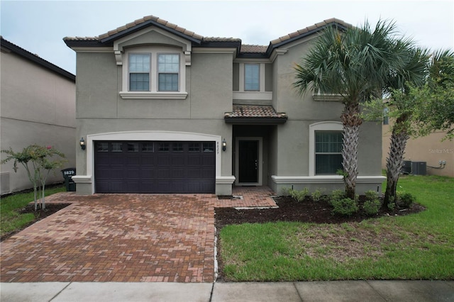 mediterranean / spanish house with decorative driveway, a tile roof, an attached garage, and stucco siding