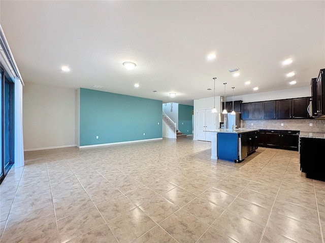 kitchen with light tile patterned floors, decorative backsplash, a kitchen island with sink, stainless steel fridge with ice dispenser, and pendant lighting