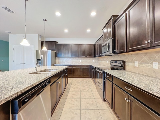 kitchen featuring dark brown cabinetry, appliances with stainless steel finishes, a sink, pendant lighting, and backsplash