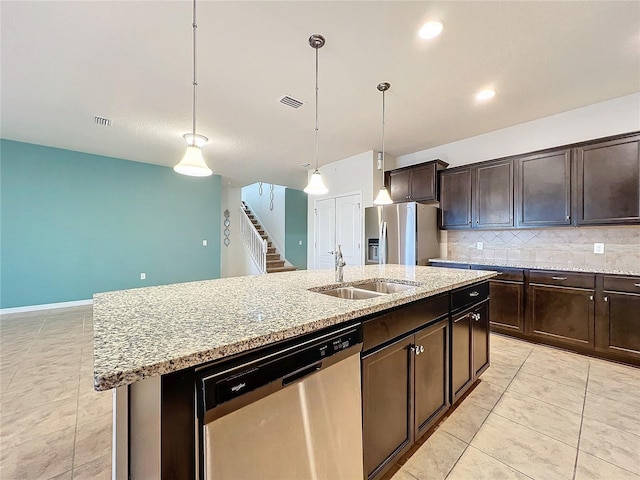 kitchen with pendant lighting, stainless steel appliances, a sink, an island with sink, and dark brown cabinets