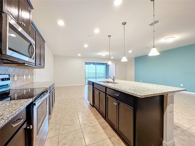 kitchen featuring visible vents, an island with sink, stainless steel appliances, pendant lighting, and a sink