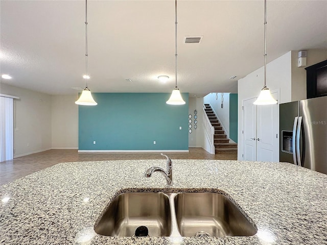 kitchen featuring stainless steel fridge, visible vents, open floor plan, pendant lighting, and a sink