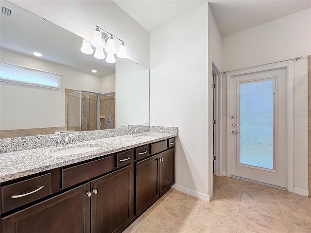 bathroom featuring double vanity, a shower stall, baseboards, and a sink