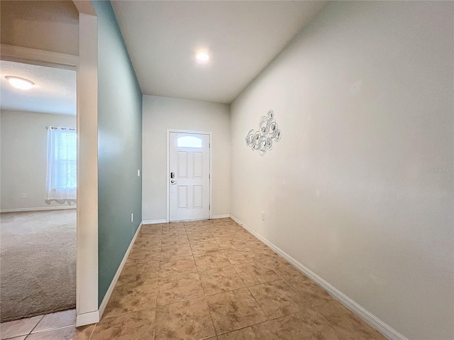 doorway to outside featuring light carpet, light tile patterned floors, and baseboards