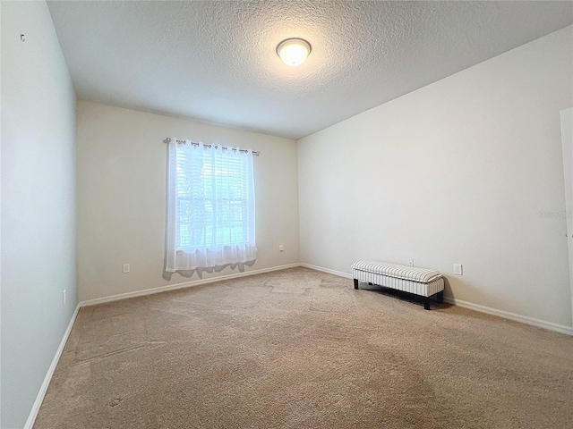 empty room with carpet, a textured ceiling, and baseboards