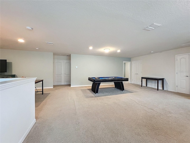 rec room with baseboards, visible vents, a textured ceiling, and light colored carpet