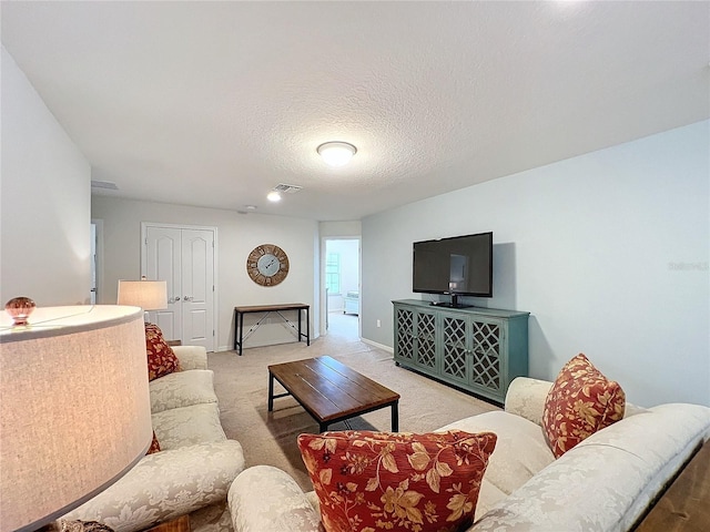 living area featuring a textured ceiling, baseboards, visible vents, and light colored carpet