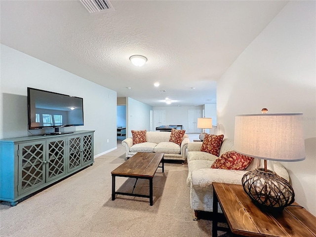 living room with baseboards, visible vents, a textured ceiling, and light colored carpet