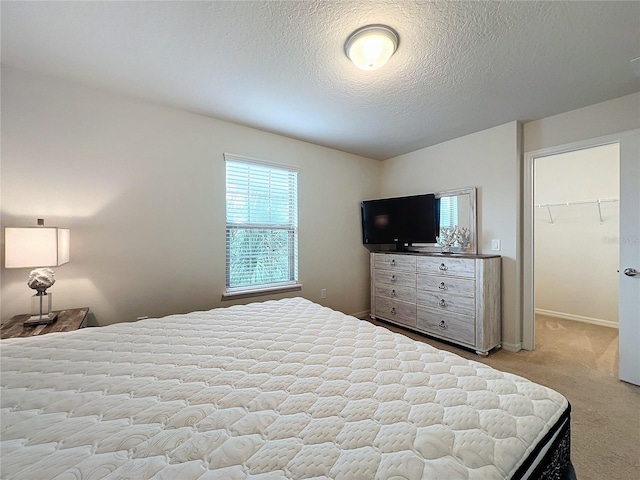 carpeted bedroom featuring a closet, a spacious closet, baseboards, and a textured ceiling