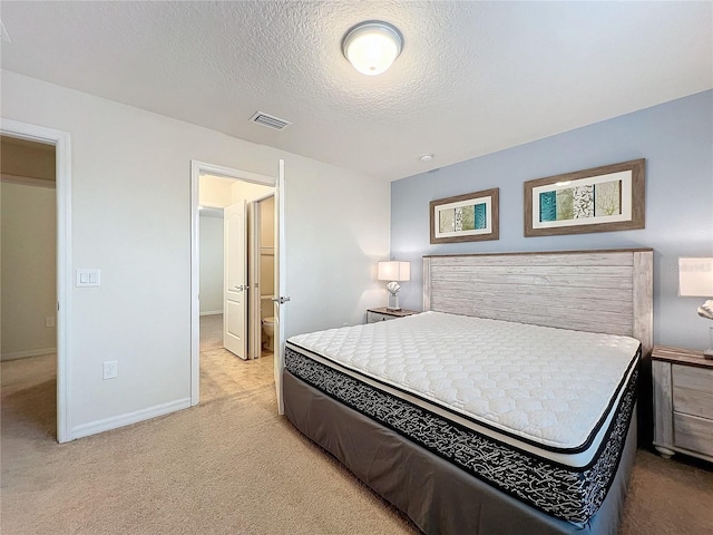 bedroom with a textured ceiling, visible vents, and light colored carpet