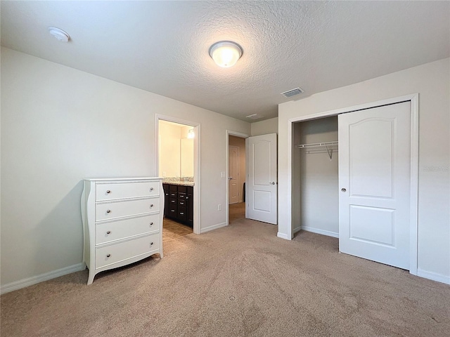 unfurnished bedroom featuring a textured ceiling, light colored carpet, visible vents, baseboards, and a closet