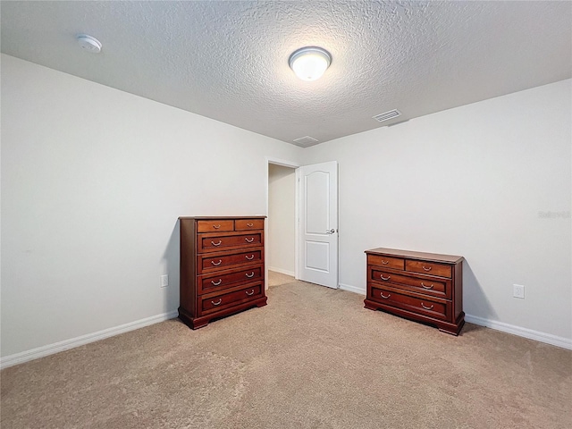 bedroom featuring baseboards, visible vents, a textured ceiling, and light colored carpet