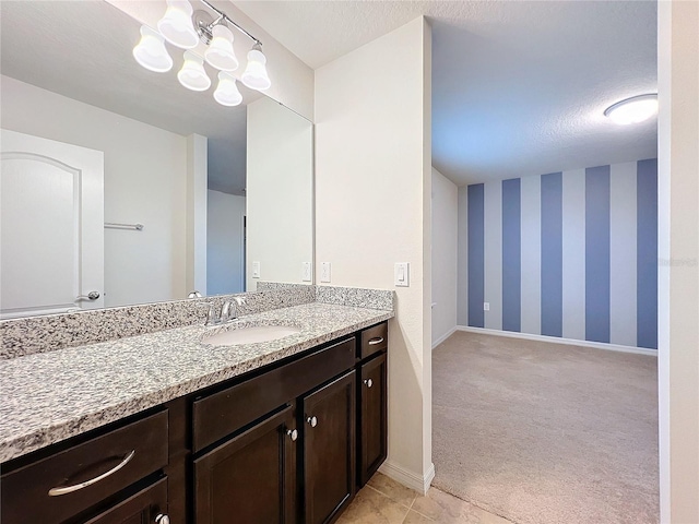 bathroom featuring a textured ceiling, a notable chandelier, vanity, baseboards, and wallpapered walls