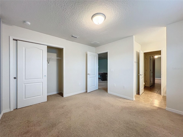 unfurnished bedroom with a closet, light carpet, visible vents, and baseboards