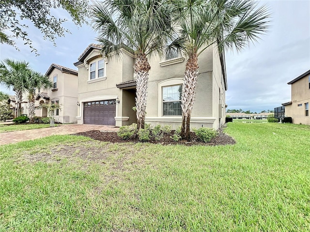 view of front of property featuring a front yard, decorative driveway, an attached garage, and stucco siding