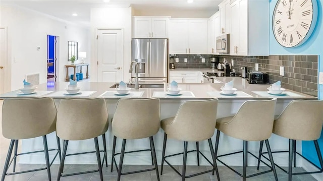 kitchen with light tile patterned floors, appliances with stainless steel finishes, tasteful backsplash, white cabinetry, and kitchen peninsula