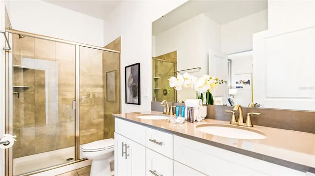 bathroom with double vanity, a sink, toilet, and a shower stall