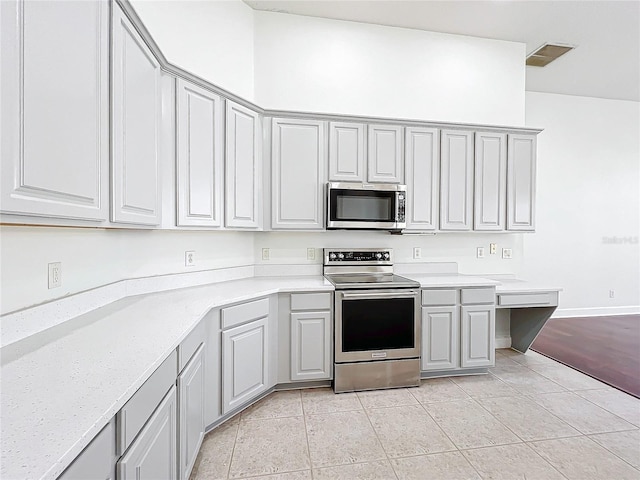 kitchen featuring gray cabinetry, appliances with stainless steel finishes, and light tile patterned floors