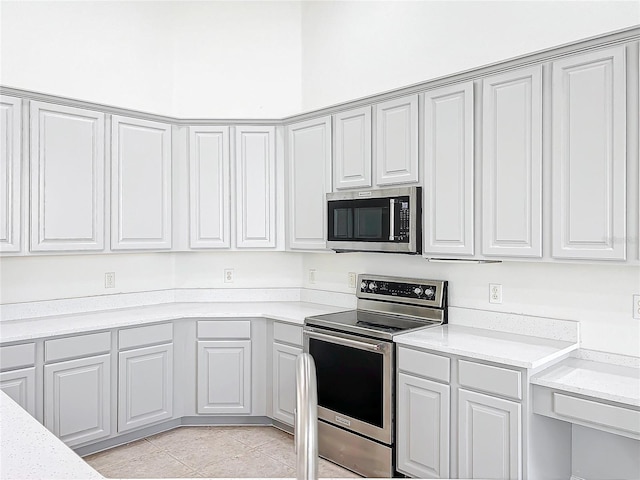 kitchen with light stone counters, appliances with stainless steel finishes, and light tile patterned floors