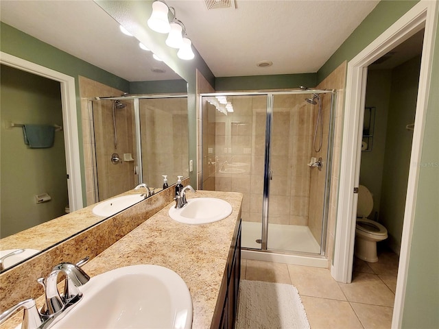 bathroom featuring tile patterned floors, vanity, toilet, and a shower with door