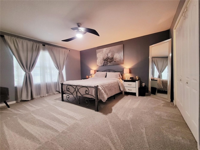 bedroom with ceiling fan, light carpet, and a closet